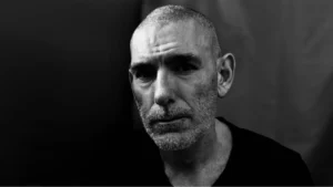 Black and white close-up portrait of a focused man with a shaved head and grizzled beard, representing the self-discipline required when learning how to do a self tape on your own in Brisbane.